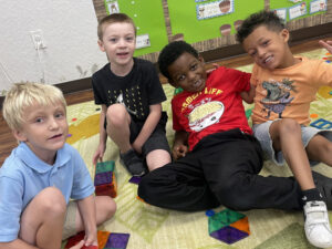 Four boys sitting on the floor playing with a toy in an Early Intervention Program at Puzzle Box Academy.