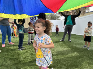 Child with vibrant parachute participating in Voluntary Pre-Kindergarten program.